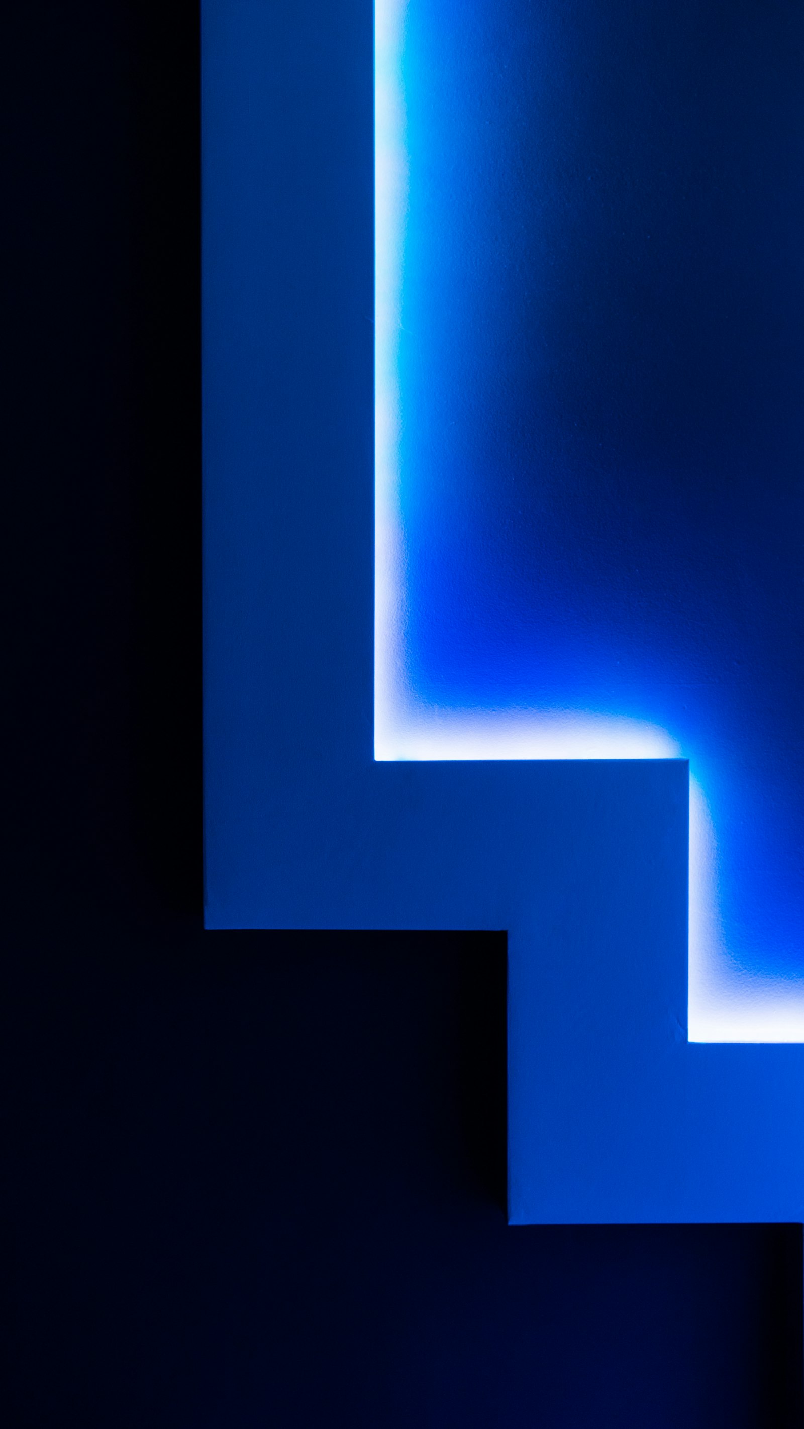 Abstract wall of stepped geometry glowing in deep blue light