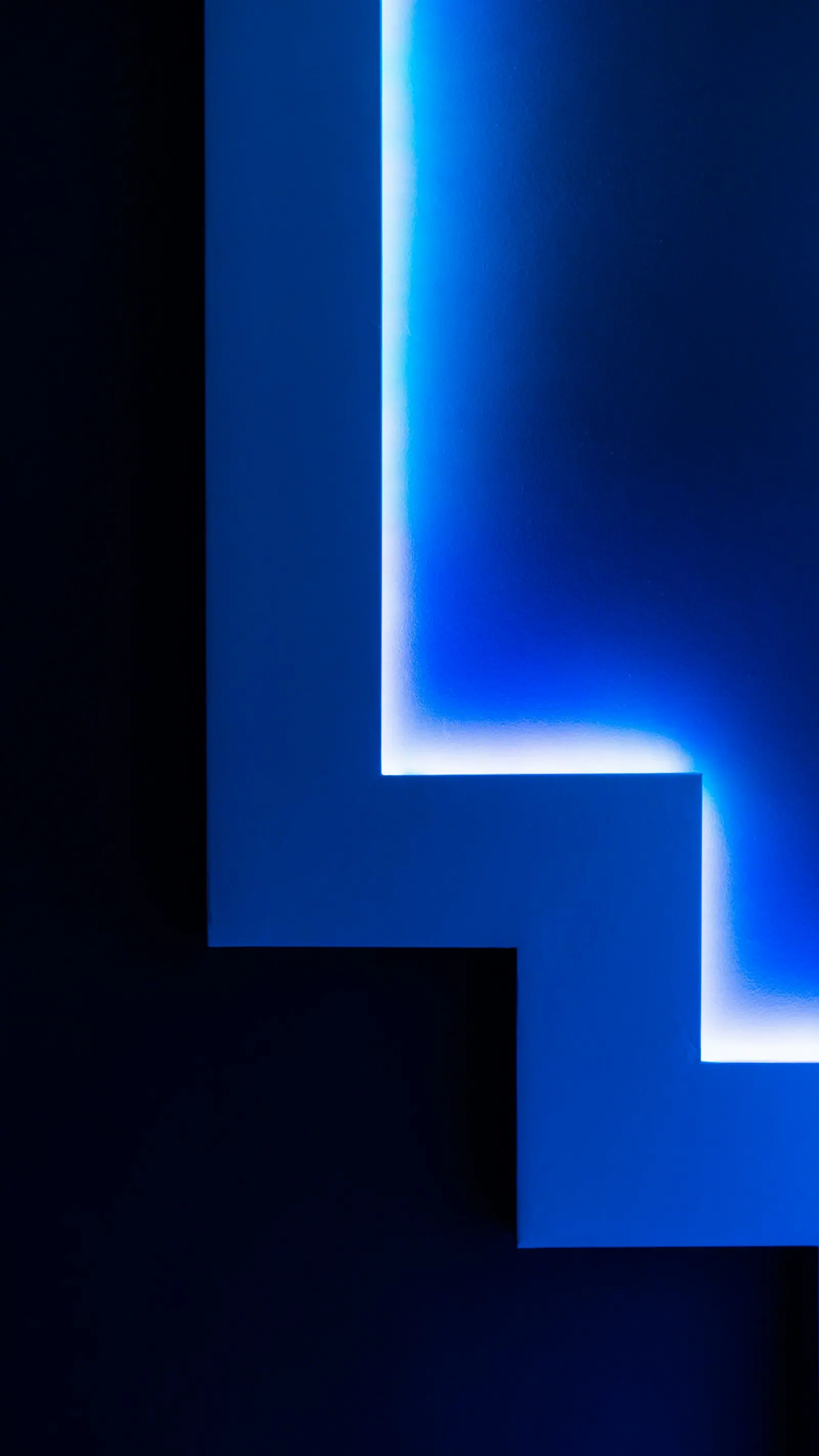 Abstract wall of stepped geometry glowing in deep blue light