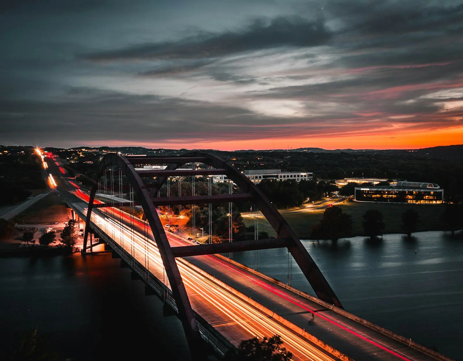 Arch bridge at dusk carrying streams of light across a river